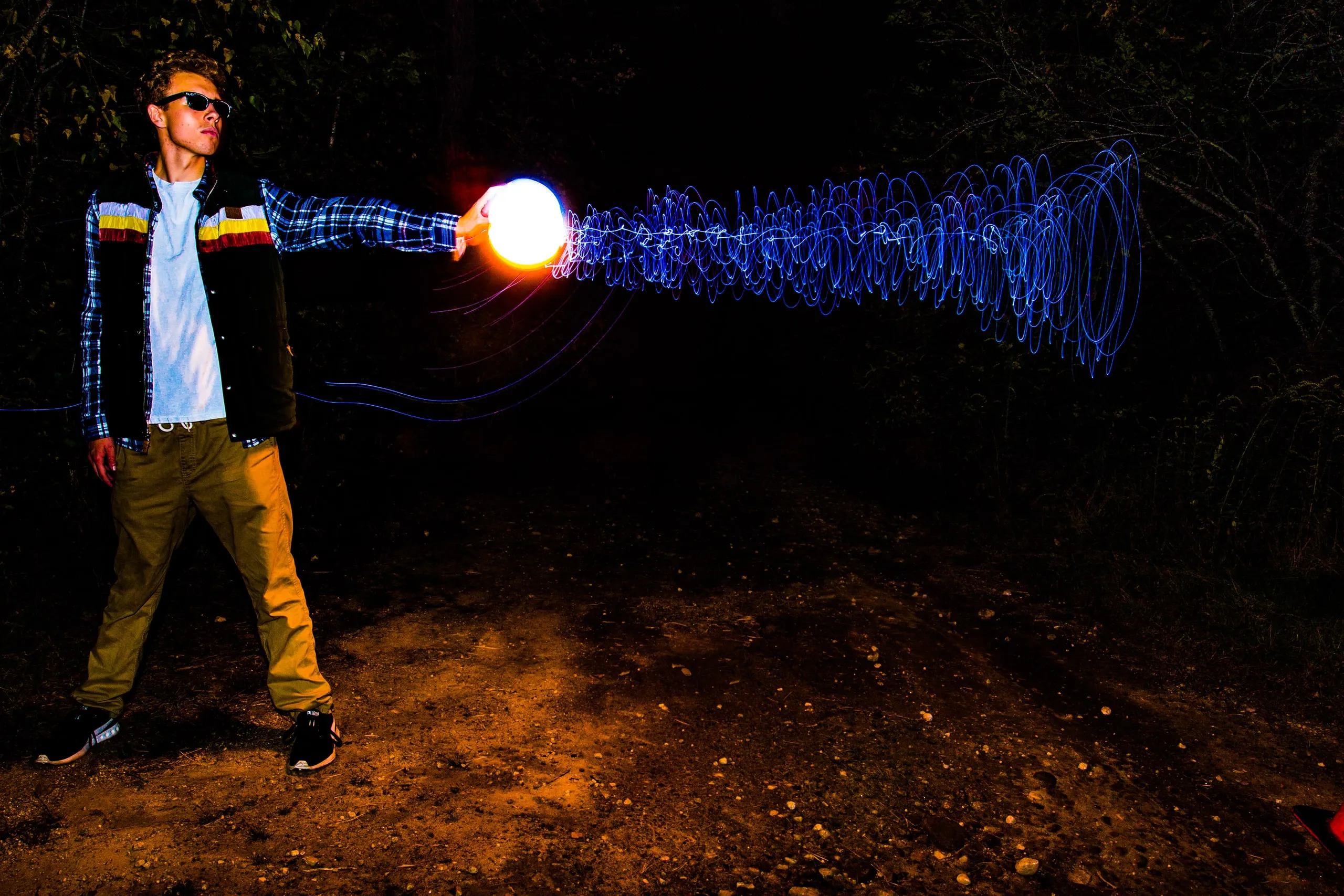 Person holding a glowing orb that streaks light across the frame