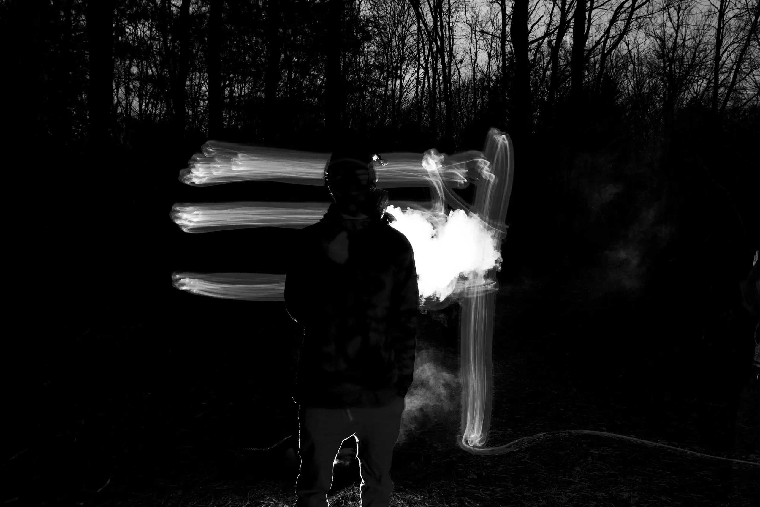 Black-and-white figure in the dark trailing streaks of white light