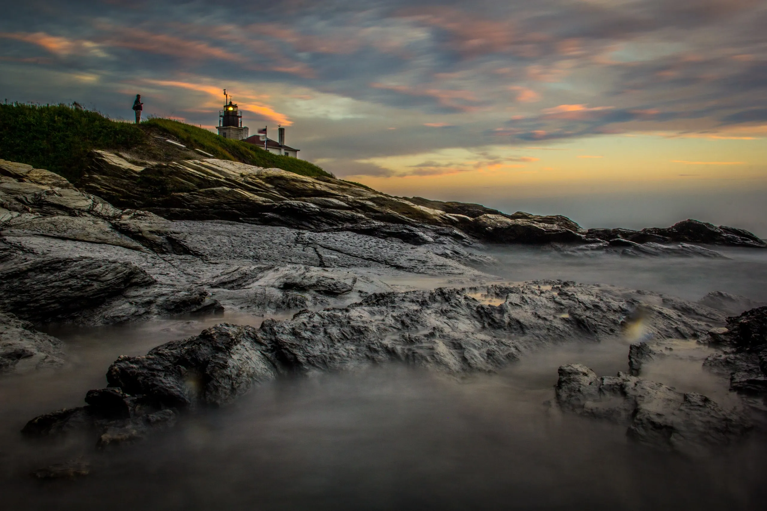Lighthouse on a rocky coastline at sunset