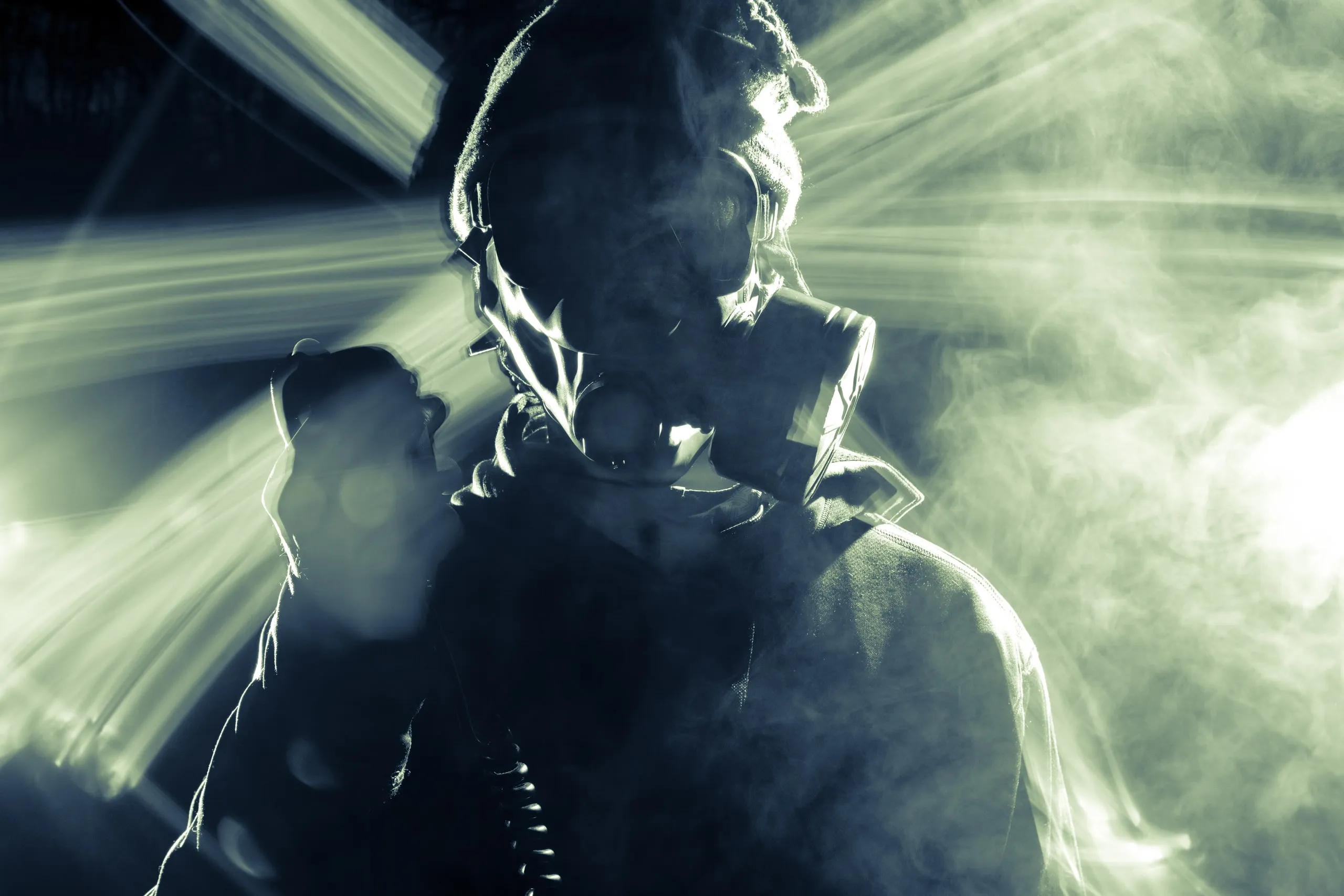 Silhouette of a person in a gas mask with beams of light behind