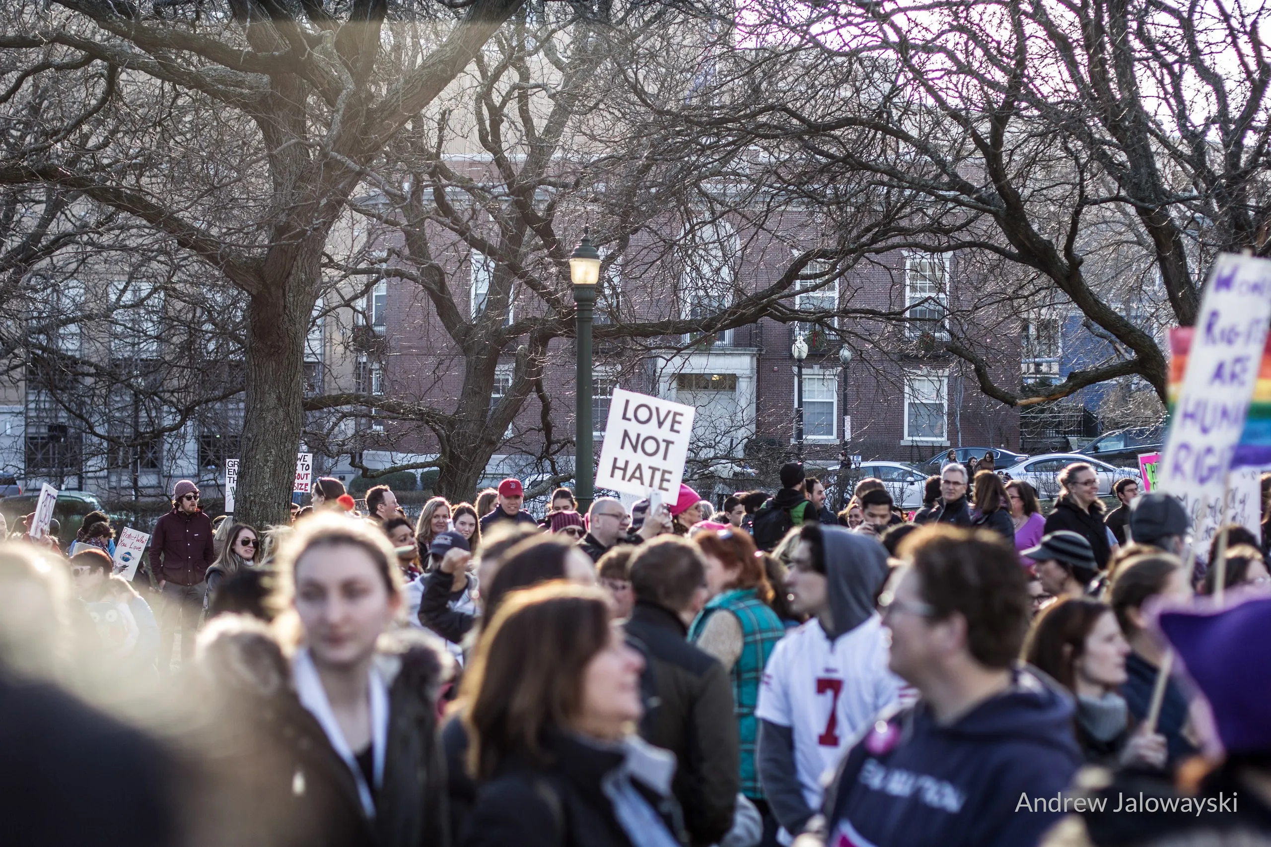 Crowd of protesters with signs marching under bare trees