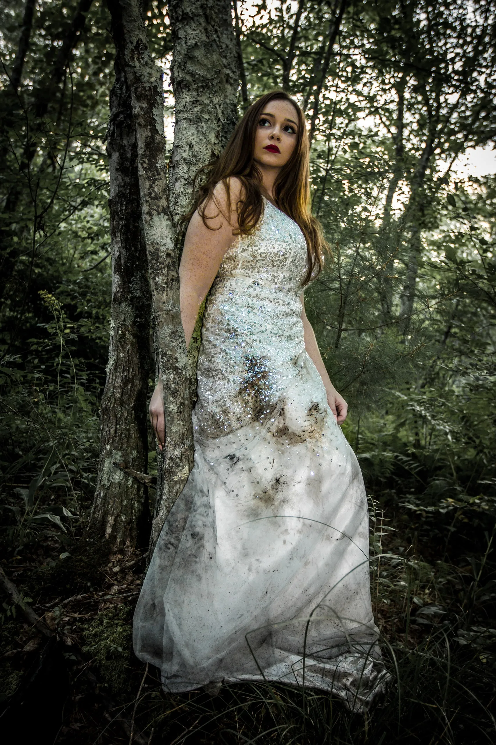 Woman in a white gown standing in a forest