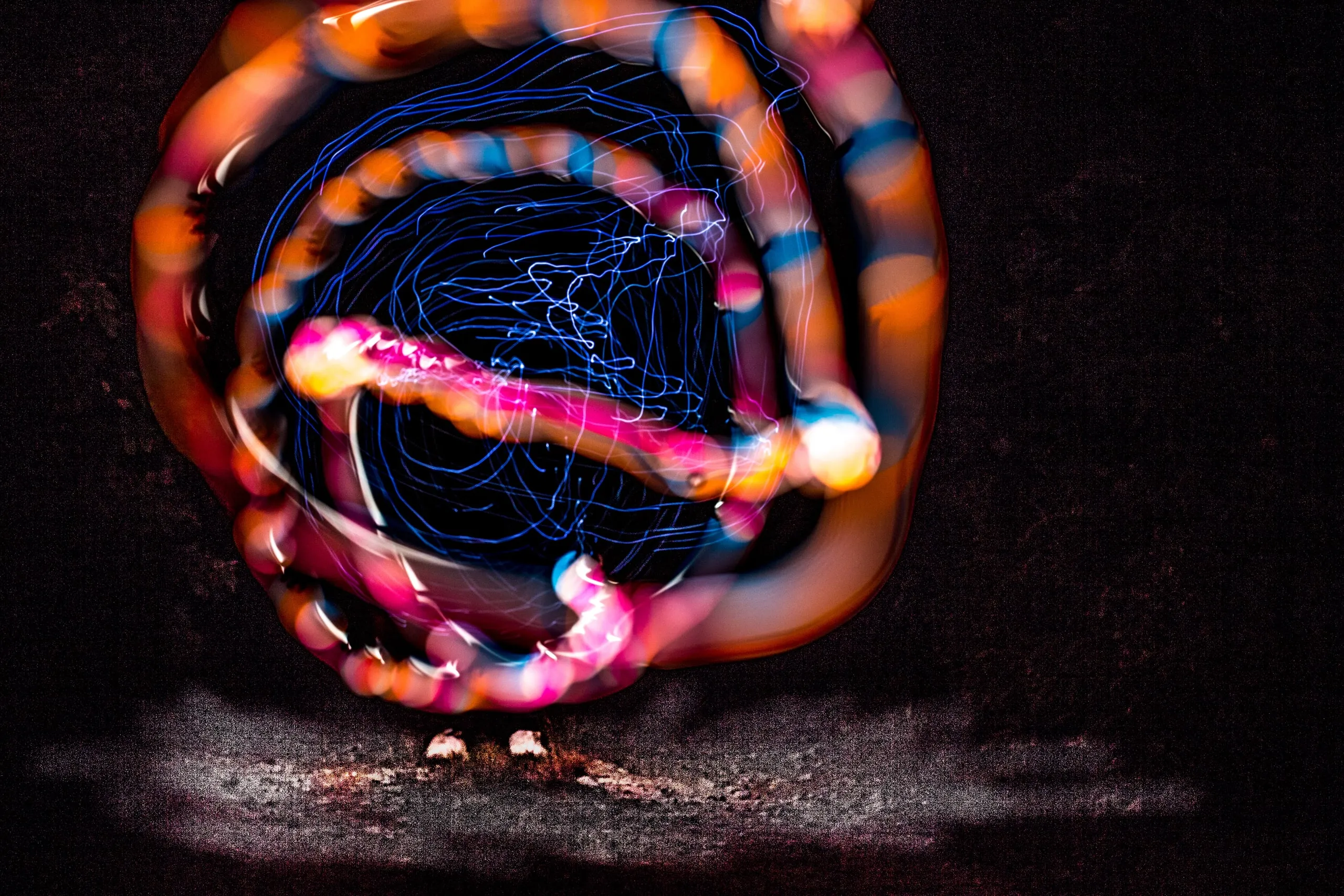 Spiral of orange and blue light trails around a glowing center