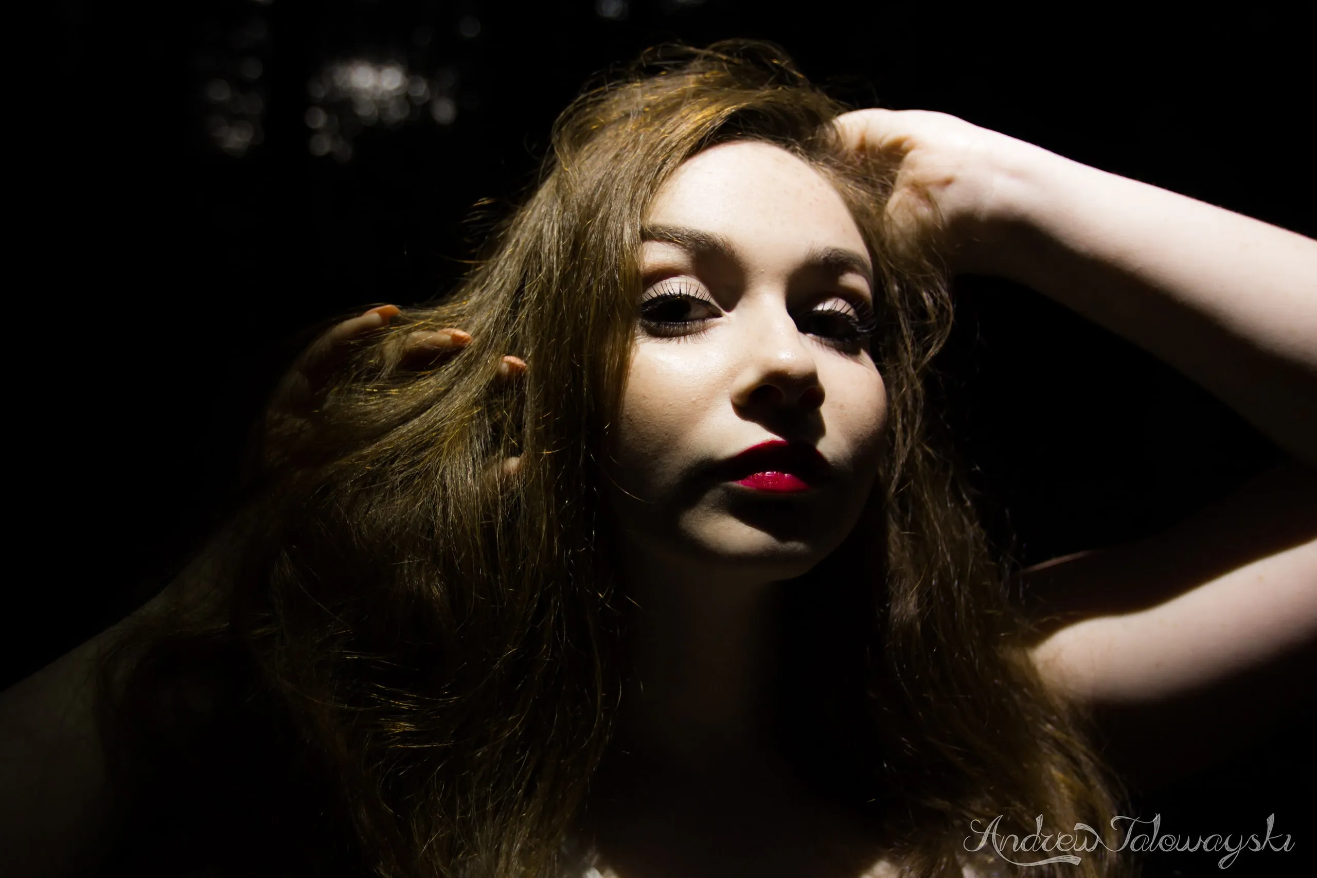 Dramatic portrait of a woman with her hand in her hair, half her face in shadow