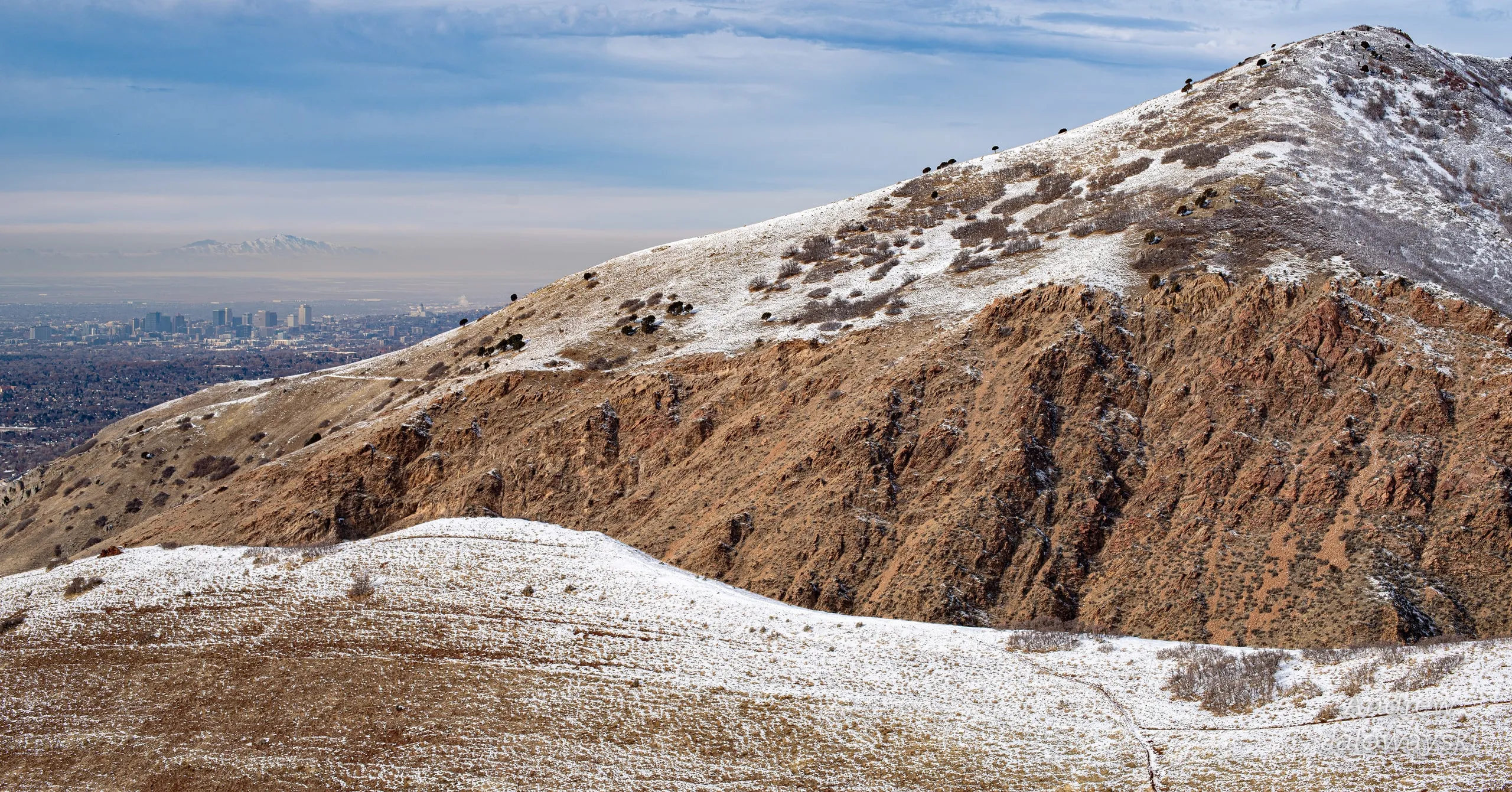 Snow-dusted brown mountain slope under a cloudy sky