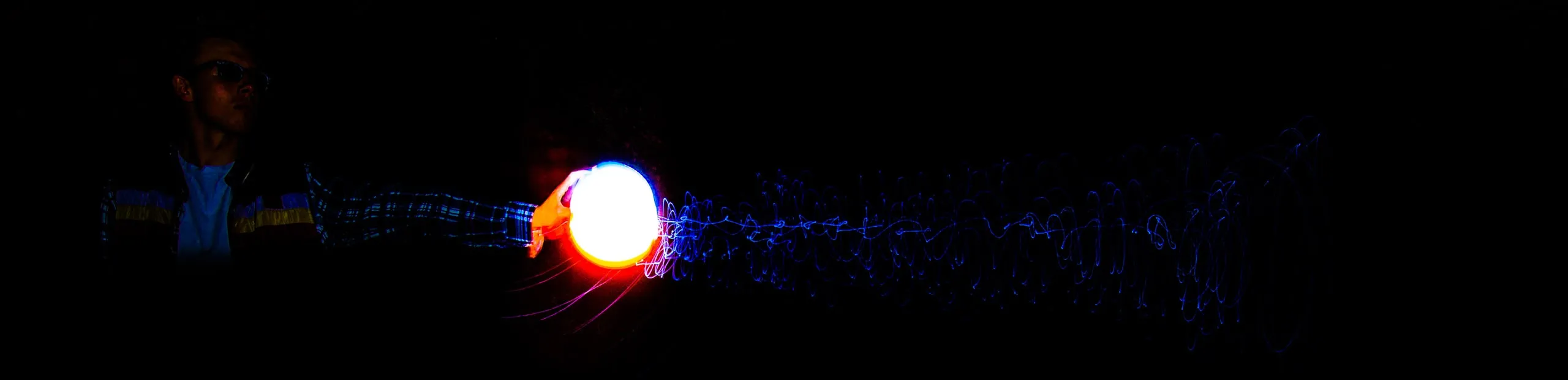 Small bright orb with a faint blue light trail in darkness