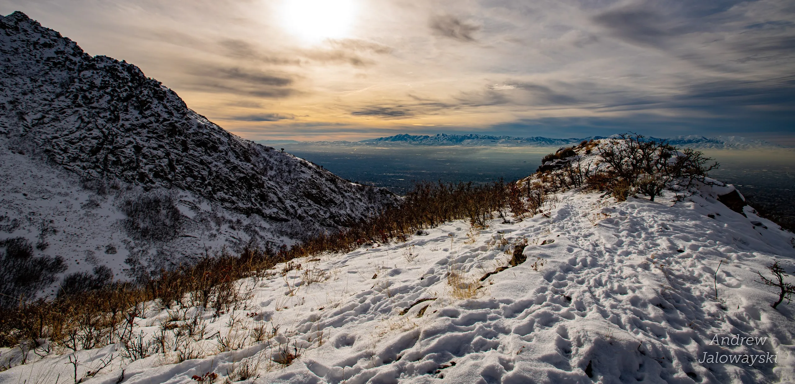 Sun breaking through clouds over snowy ridges and the valley