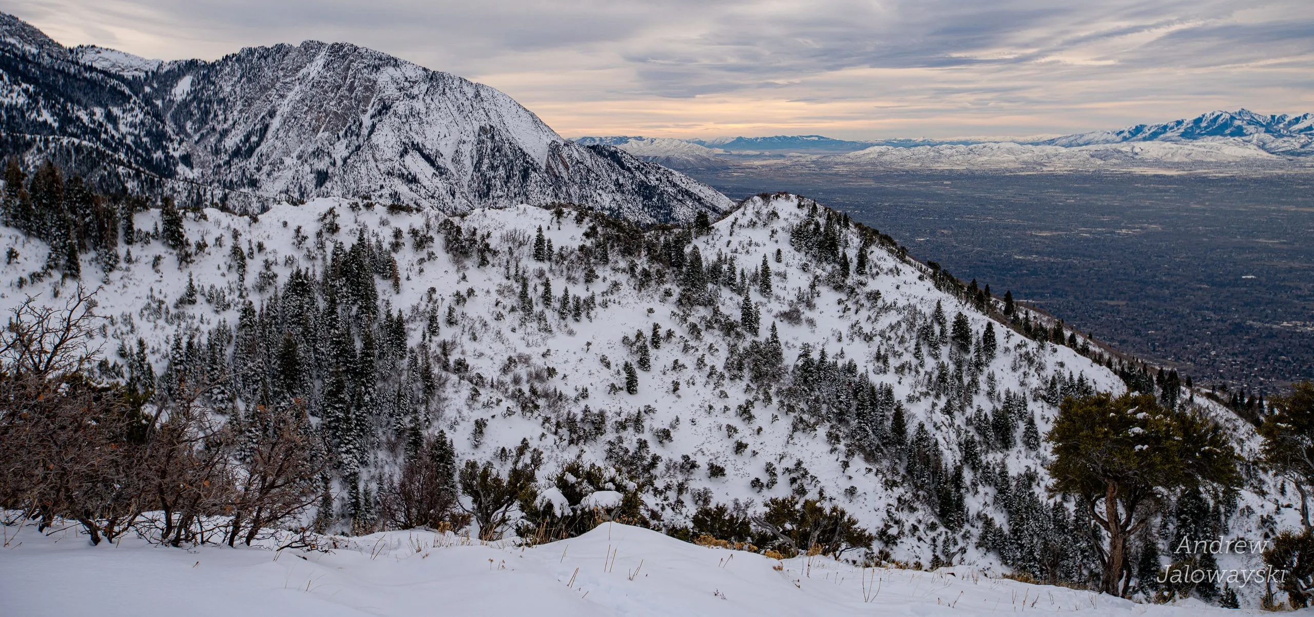 Snow-covered mountainside dropping toward the city below