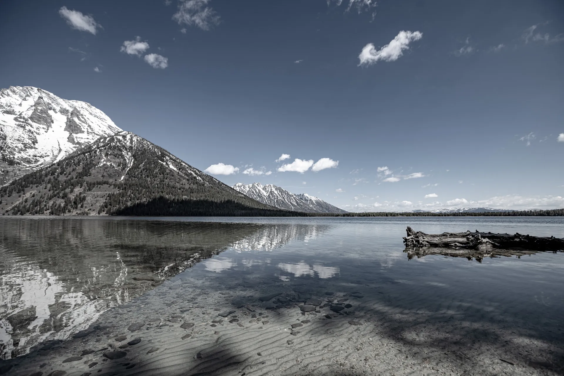 Black-and-white view of snowy Teton peaks reflected in a still lake