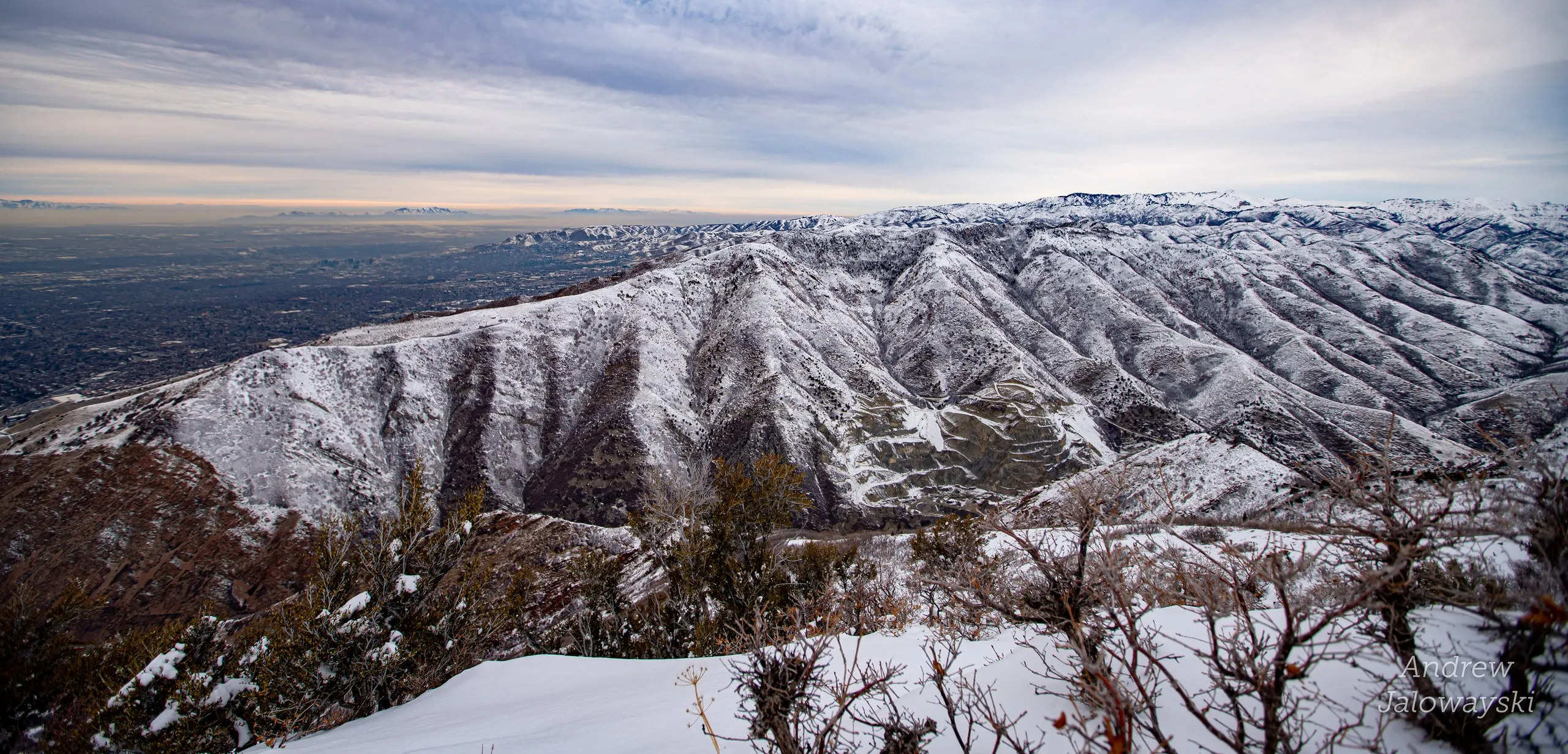 Snowy ridgeline with brush under a streaked sky