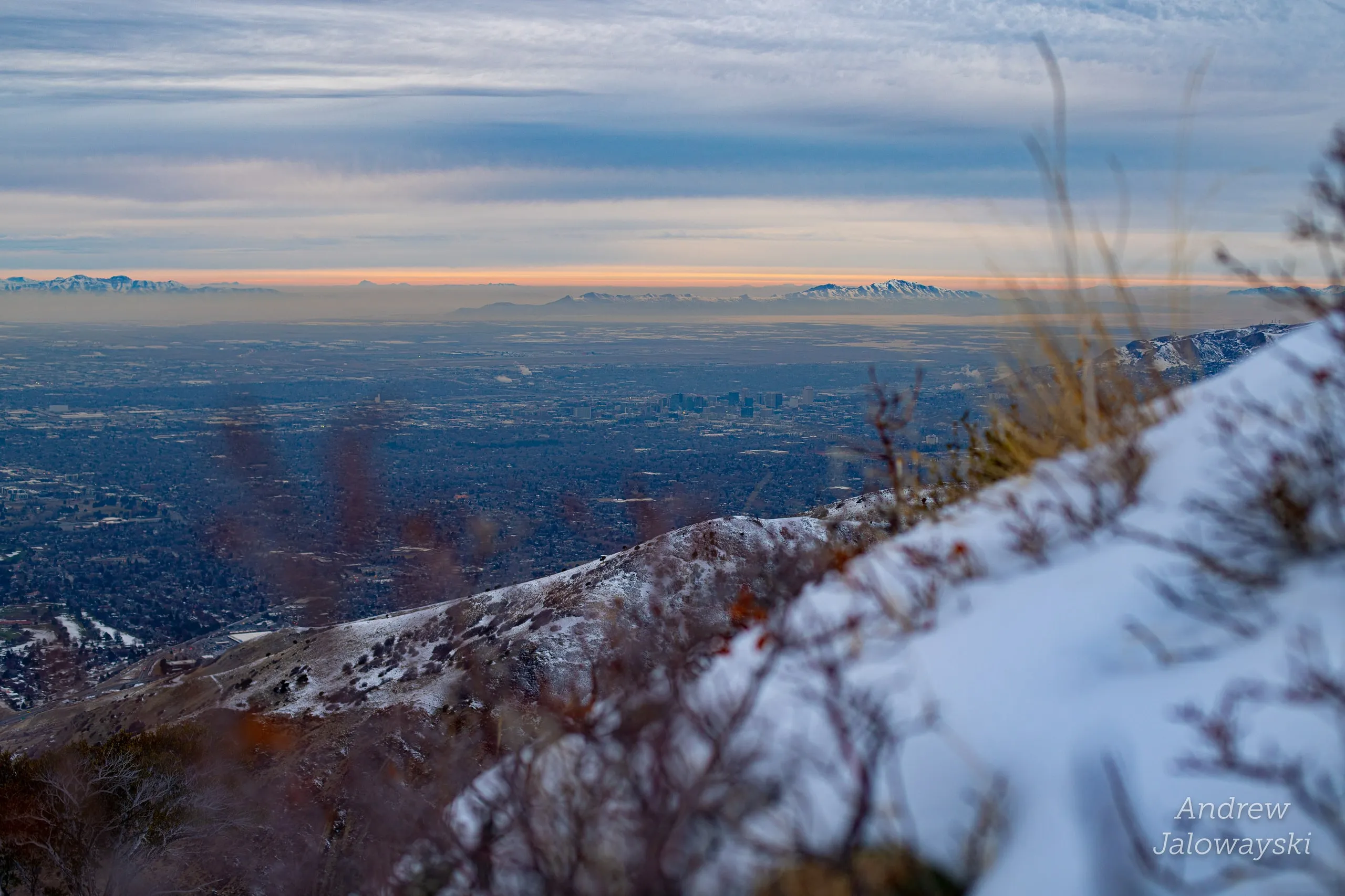Dry grass on a snowy slope above the hazy valley