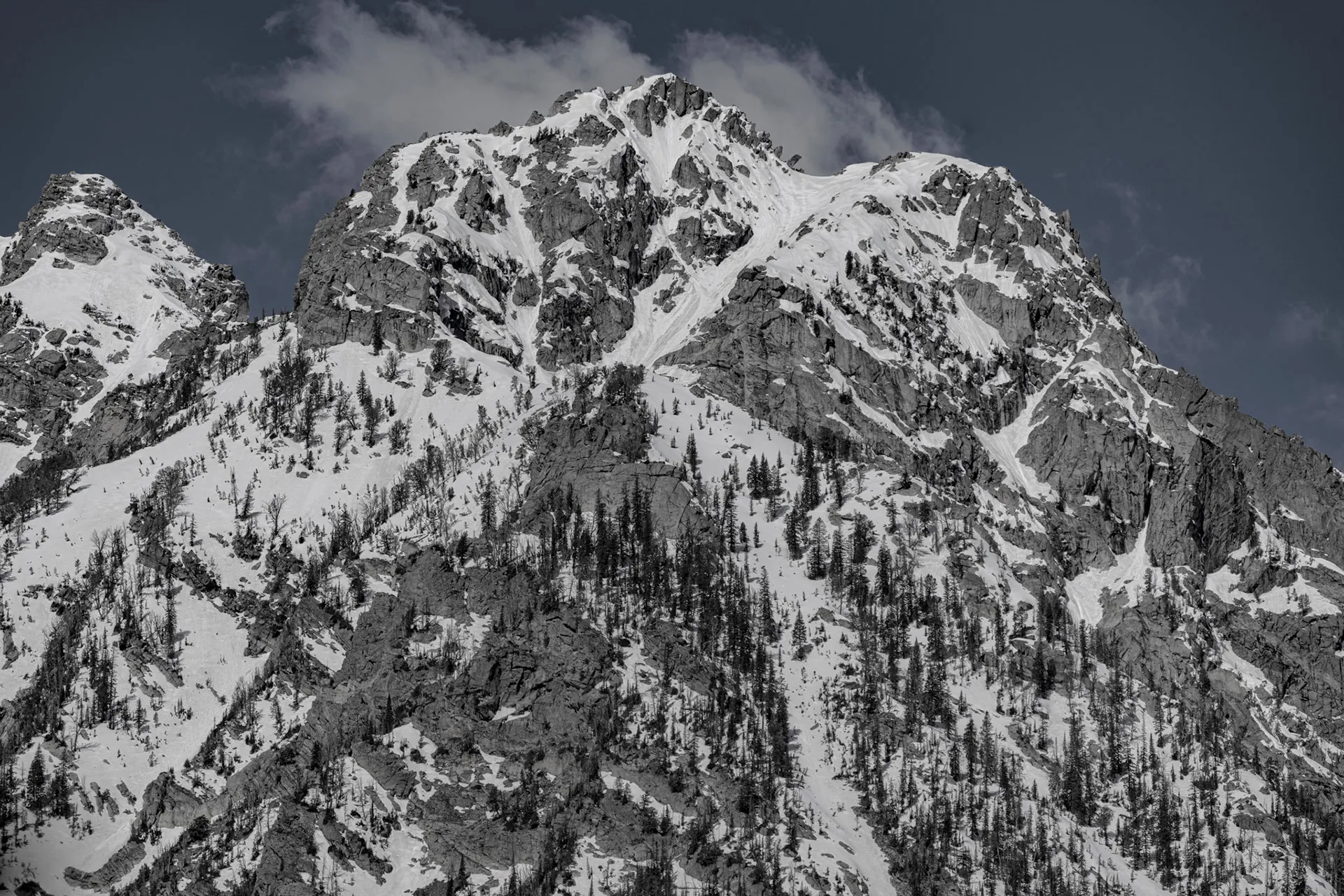 Jagged snow-covered Teton peak against a cloudy sky