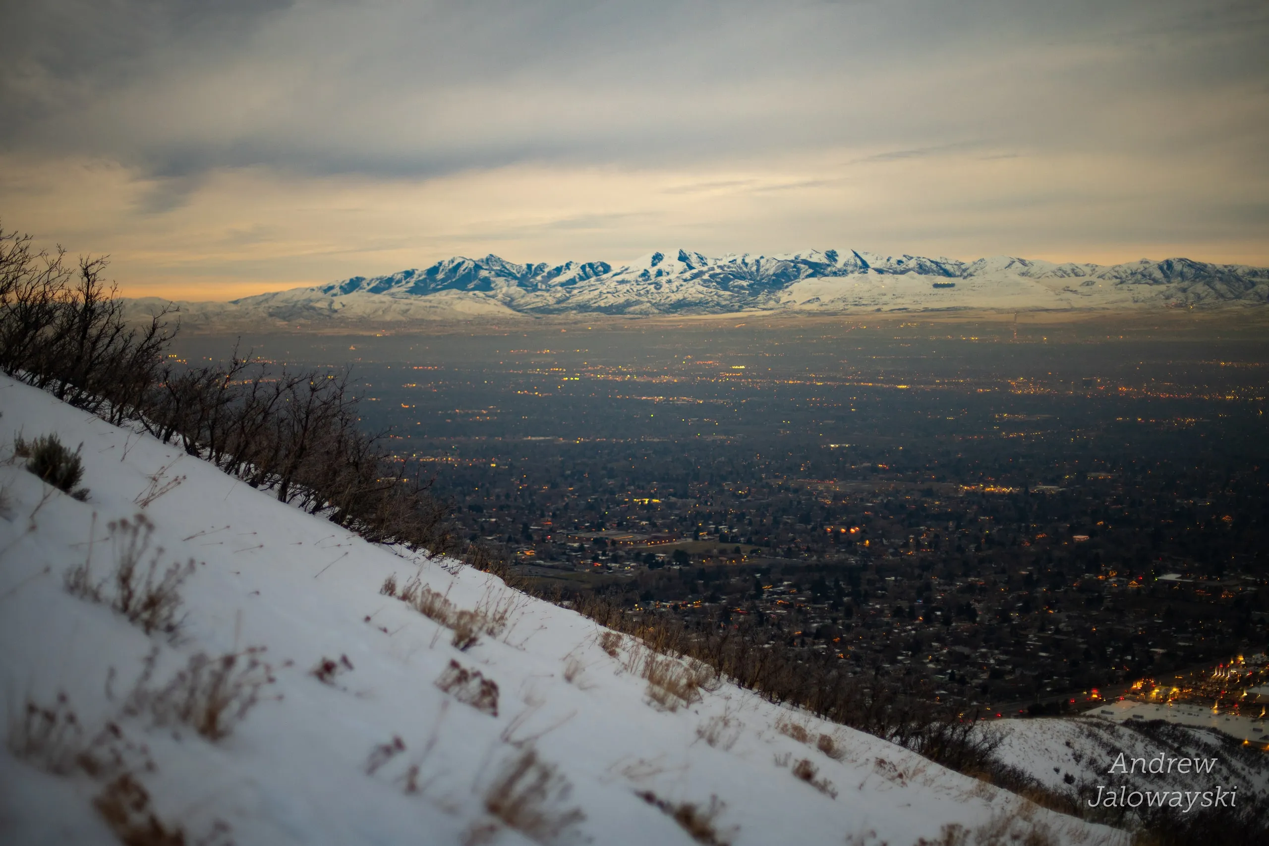 Snowy slope with dry brush above the twilight valley