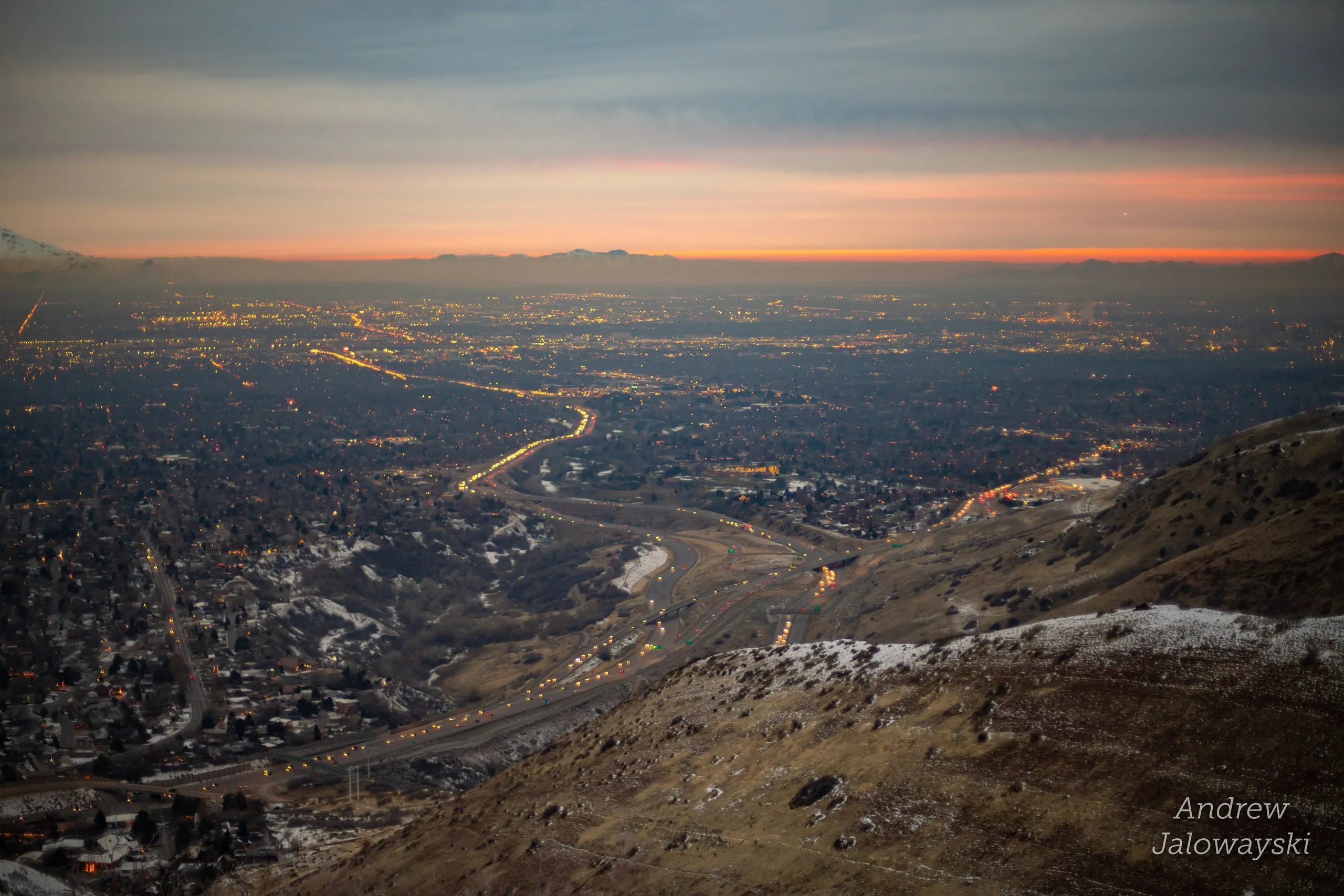 City lights spreading across the valley under an orange sunset