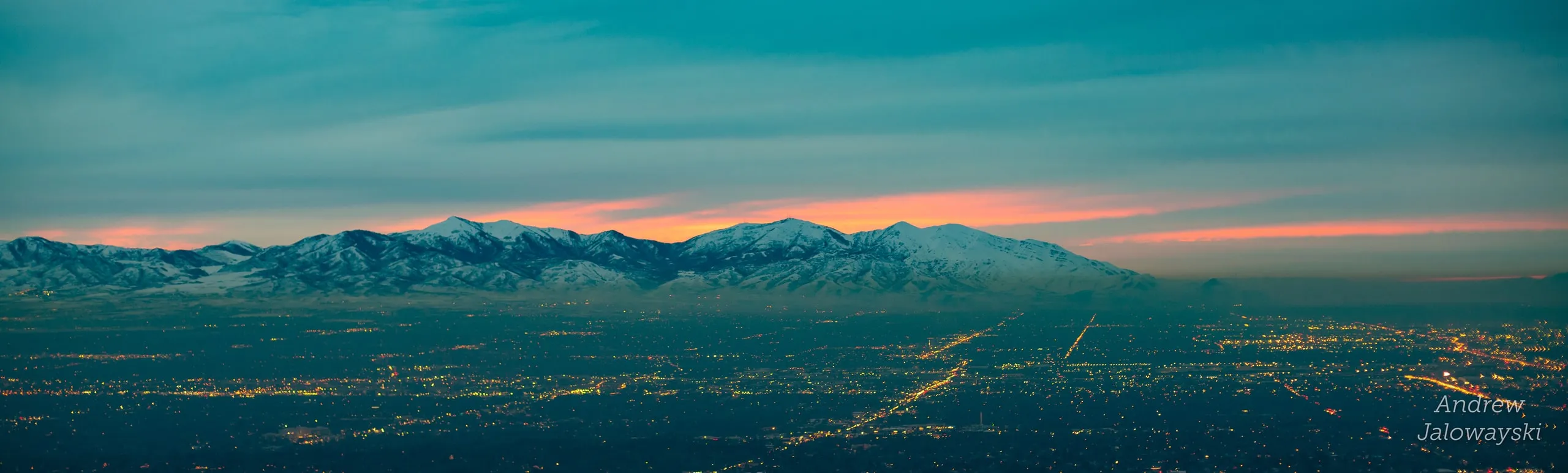 Mountains across the valley under a teal and pink sky