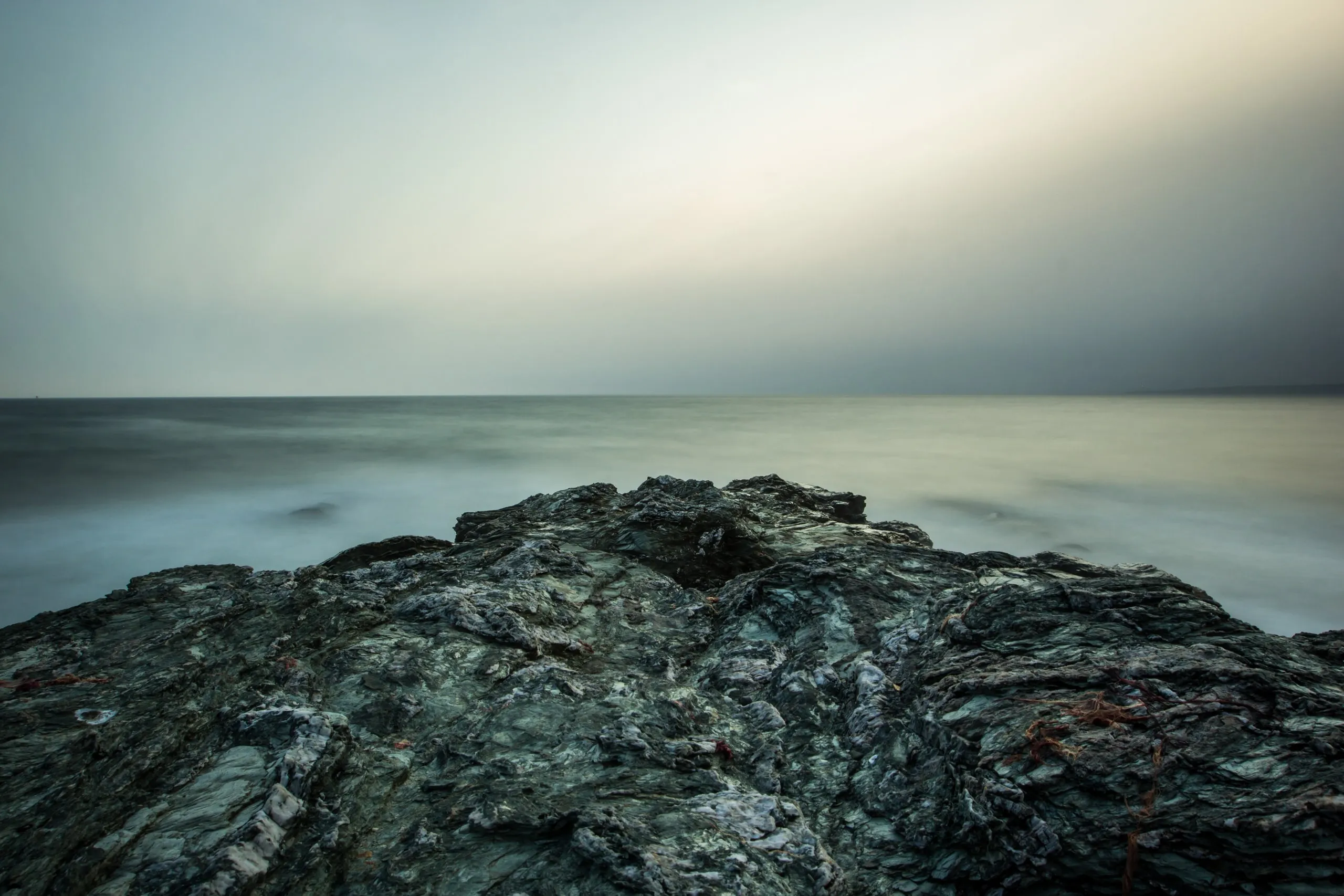 Long-exposure ocean softened into mist around dark coastal rocks