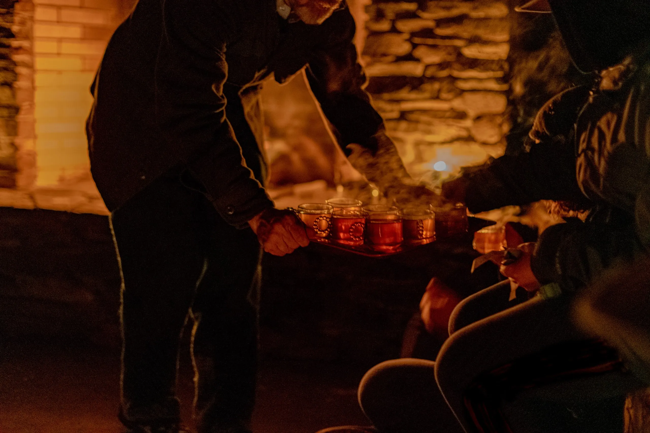 Hands and faces lit by candlelight in a dark room