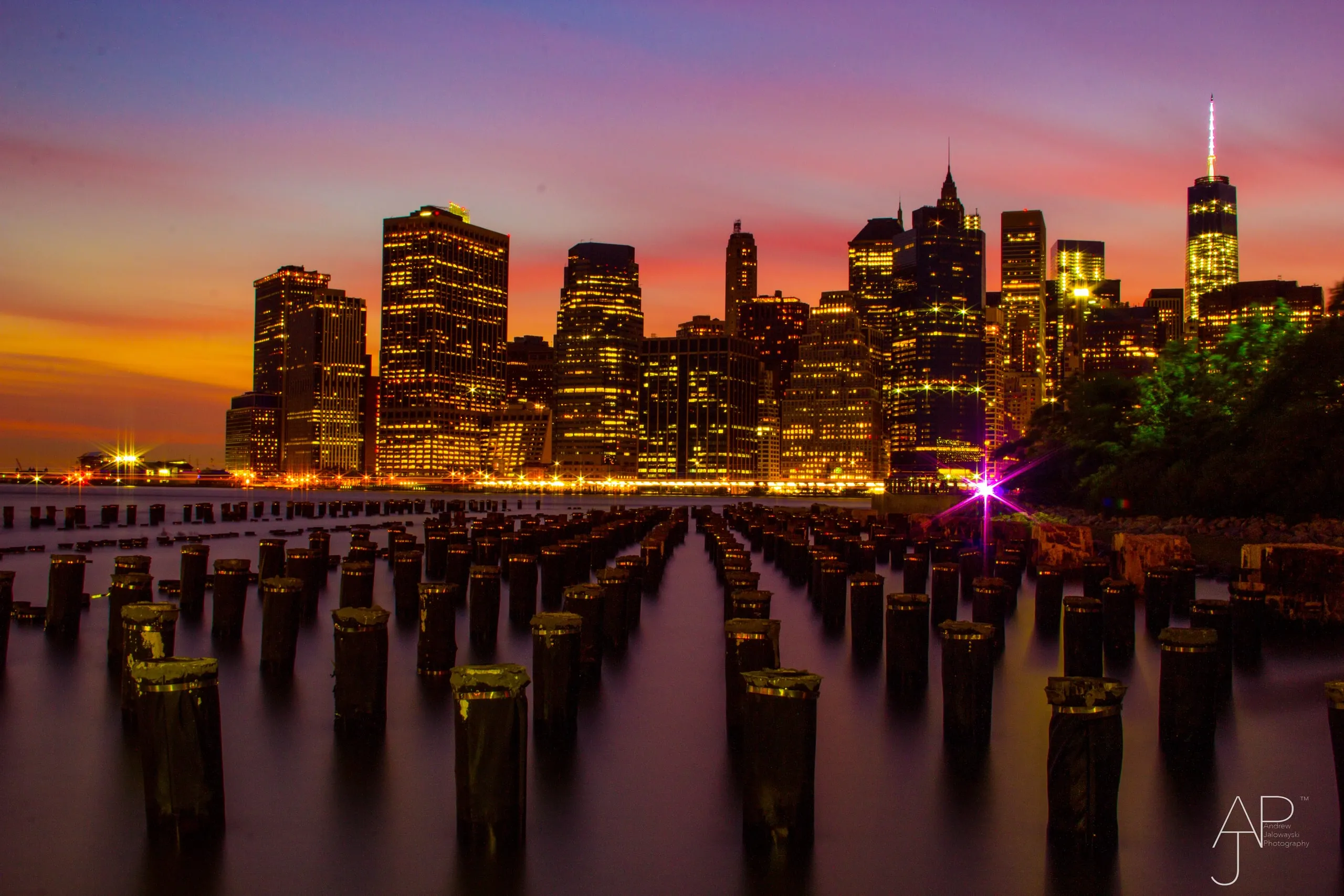 Old pier pilings in the water in front of a city skyline at sunset